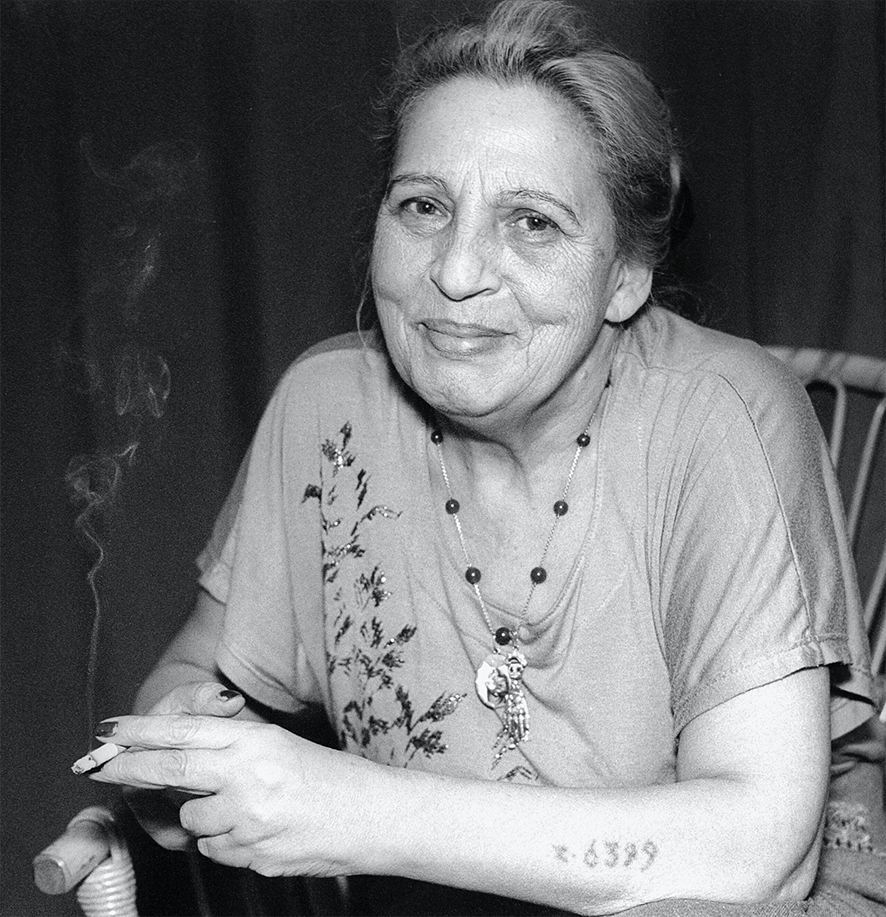 Svartvitt porträtt av Ceija stojka med en cigarett i handen och siffrorna tatuerade på armen.
