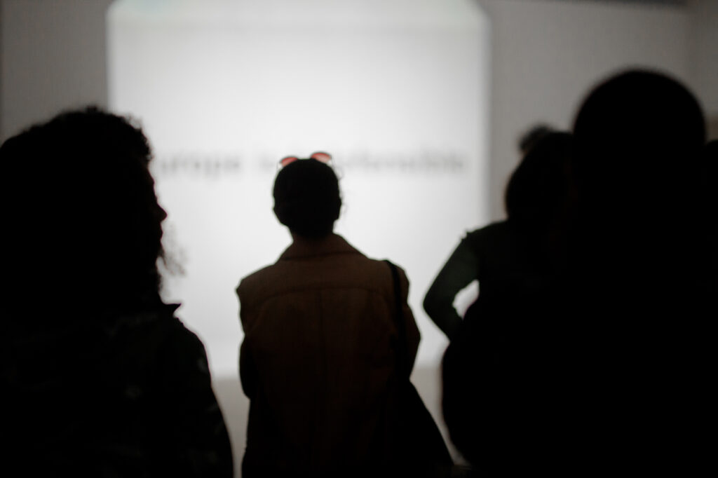 Picture taken from behind of a group of people listening to something in Malmö Konsthall.