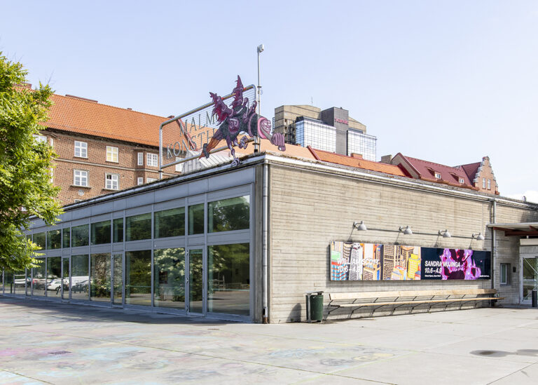 Exteriörbild av konsthallens gavel ut mot piazzan. Kim Demånes skulptur hänger i skylten