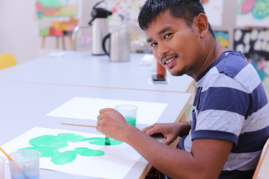 Deltagare i konstlyftet målar i akryl på ett papper