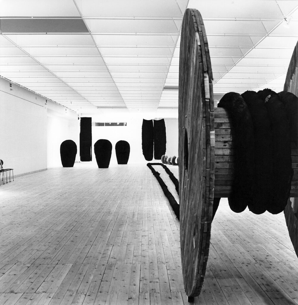 Utställningshallen med stora textila installationer och ett stort trähjul.