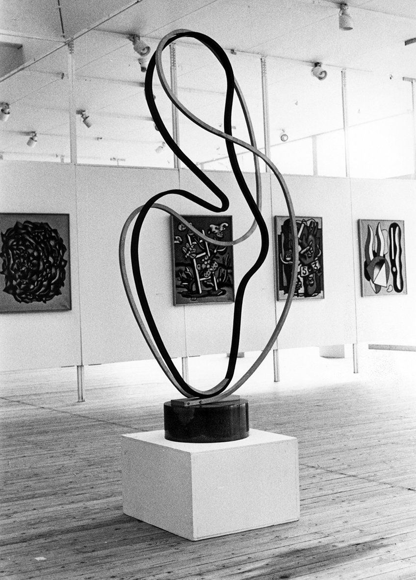 Installation view of an organic, graceful sculpture. Other works can be seen in the background.