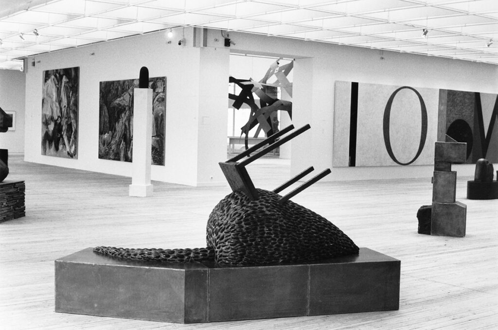 Konstverk i utställningshallen. Närmast kameran står en skulptur med en liggande stolform av SIgurd Gudmundsson.