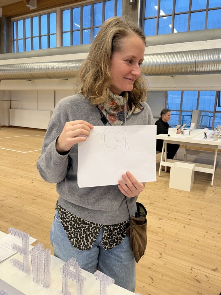 Kvinna håller i ett vitt papper med en streckteckning
