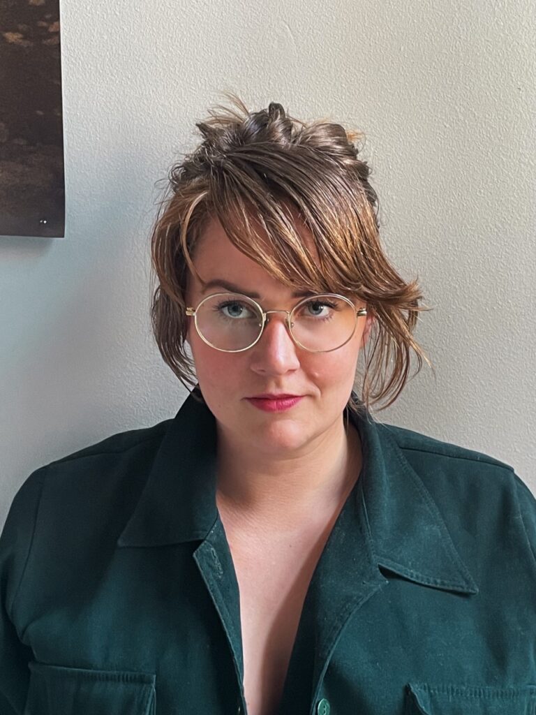 Porträtt av yngre kvinna i glasögon och grön blus