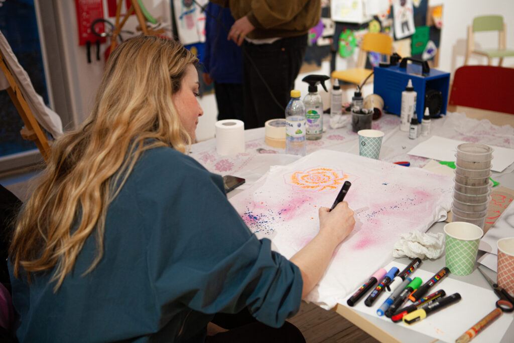 Bild av ung kvinna omgiven av konstnärsmaterial som skapar i konsthallens verkstad.