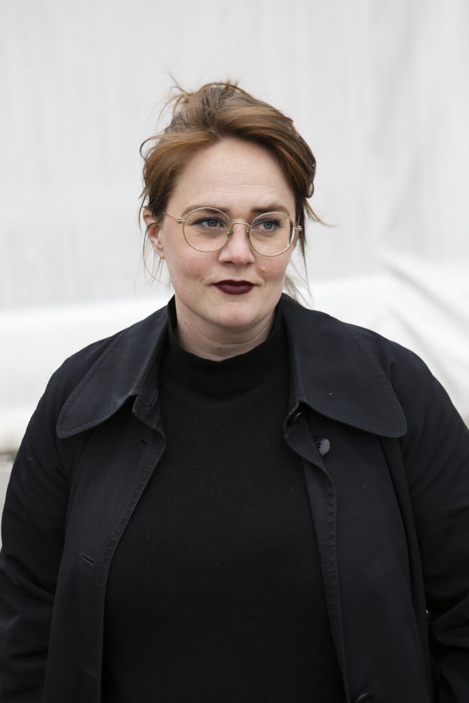 The artist Jennifer Sameland; wears round glasses and is dressed entirely in black.