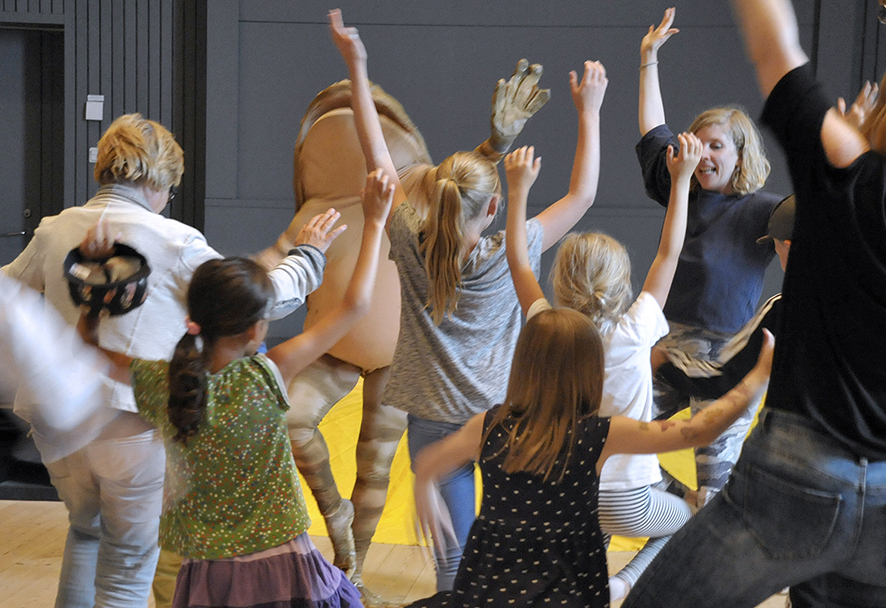 En person i groddräkt dansar med en grupp barn.