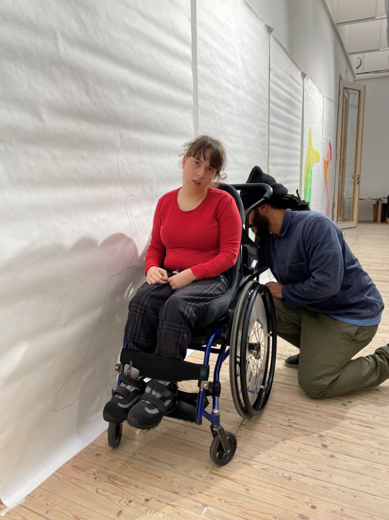 Kim Demåne målar en siluett av en person i rullstol.