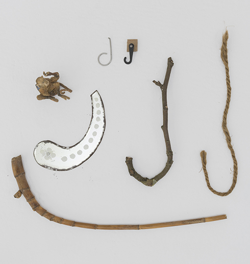 Collection of objects, such as sticks, seed pods, and ropes in the shape of the letter J.