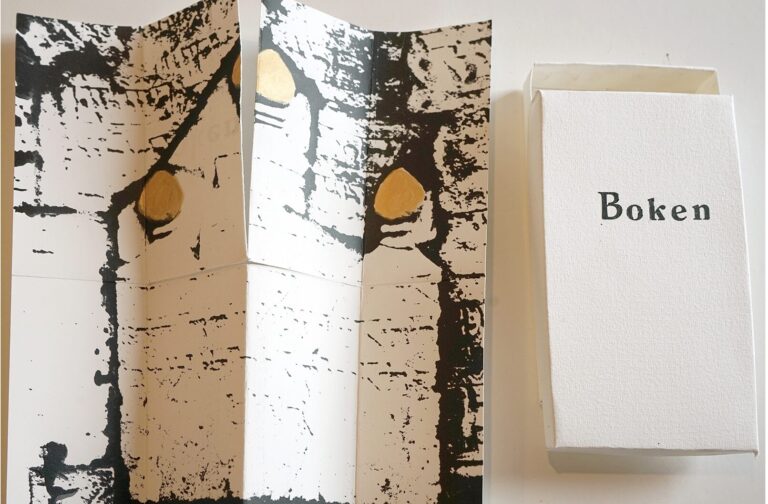 Vit ask med text "Boken" samt uppvikt folder som ser ut att passa i asken.