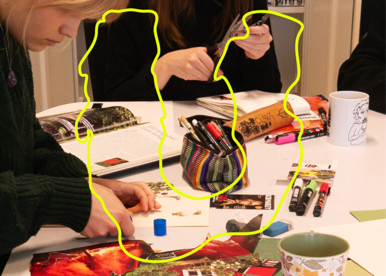 Två tonåringar sitter och pysslar med ett collage. Bilder, lim och saxar ligger framme på bordet.