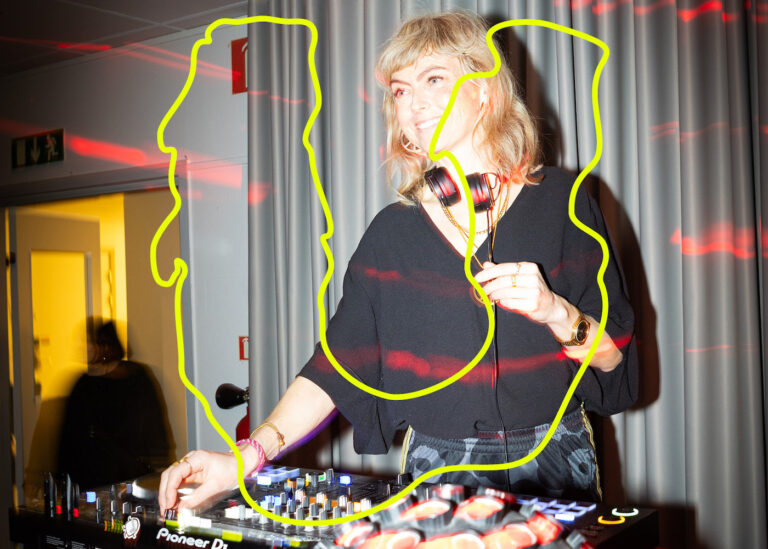 Kvinna med hörlurar runt halsen framför DJ-utrustning