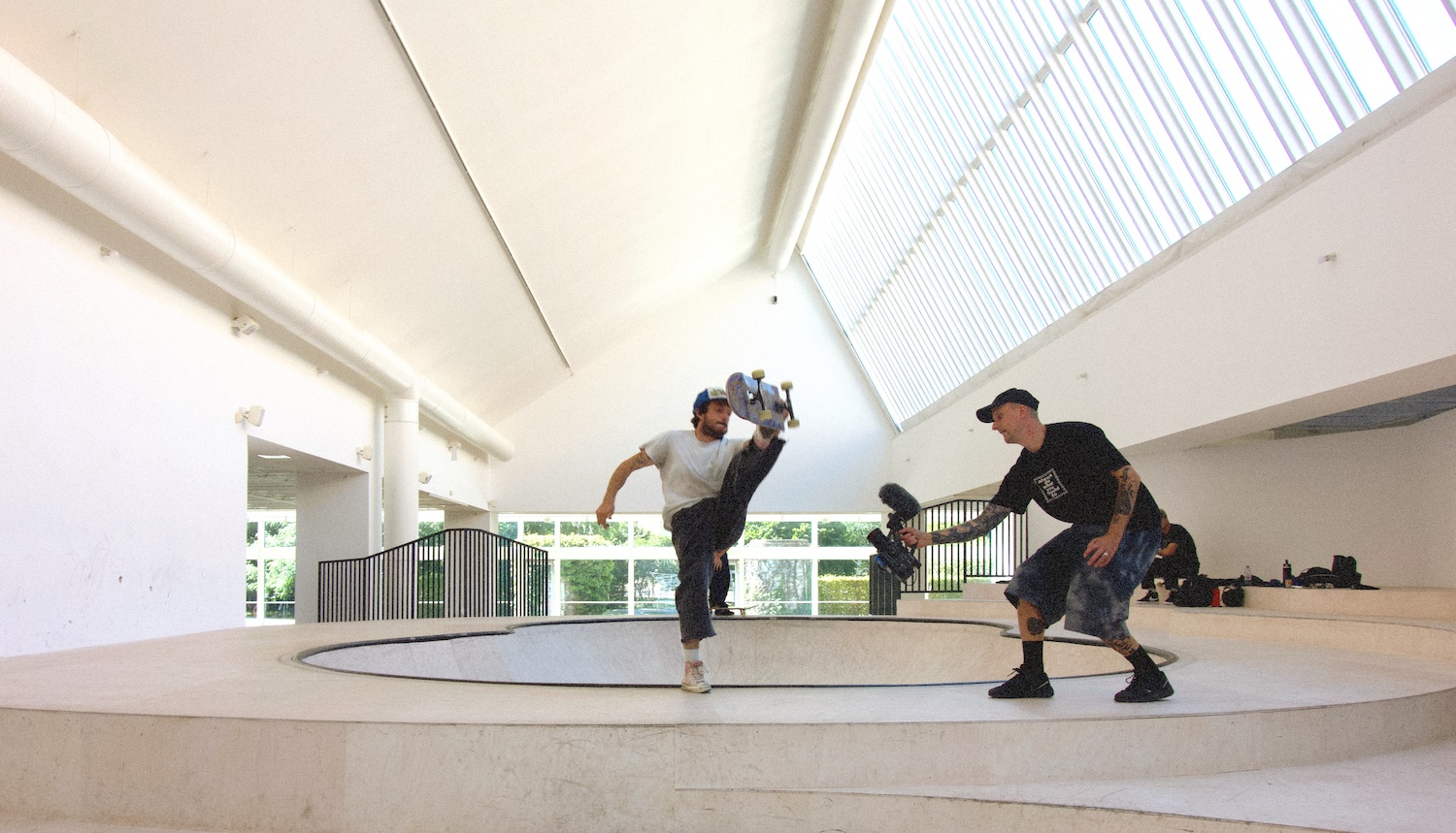 Skateboardåkaren Dylan Flucher gör ett akrobatiskt trick i KOO JEONG A'S skulptur på Malmö Konsthall. Till höger om honom filmar Markus Bengtsson hans rörelser.