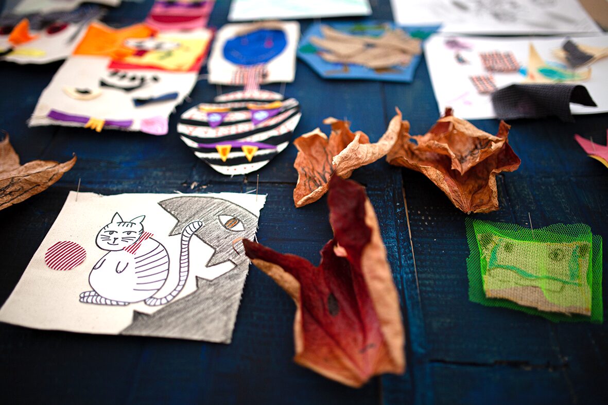 Various autumnal artworks in textiles along with some dry leaves.