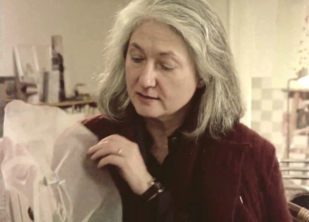 Still image from the film 'The Artist Lenke Rothman' with Lenke Rothman in her studio in New York, holding one of her works