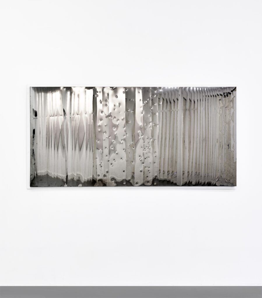 A rectangular, horizontal artwork in sheet metal with engravings that reflect the viewer.