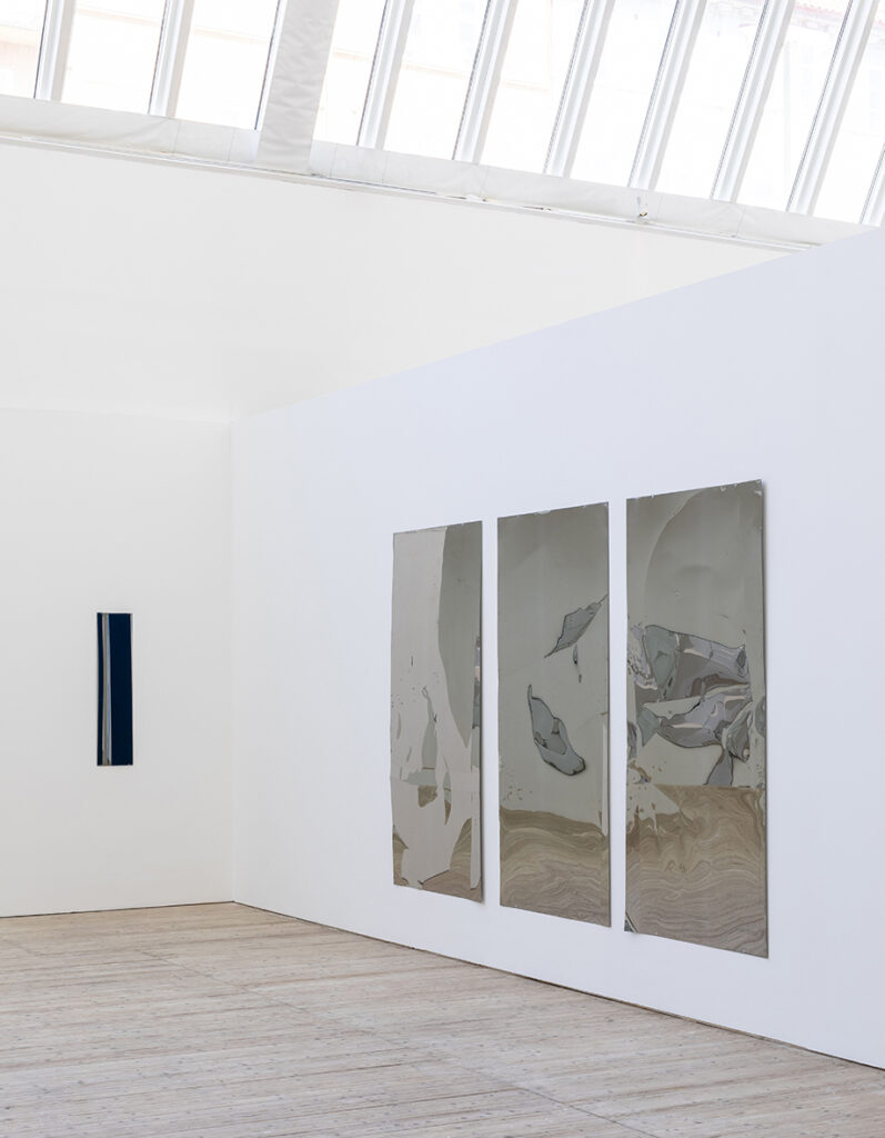 Installation view of Lars Fredrikson – three machined metal mirrors hanging on a wall.