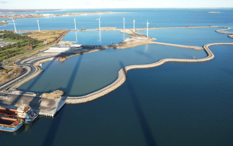 Flygbild över Lynetteholm, en konstgjord halvö, som visar anläggningsarbetet och omgivande vatten.