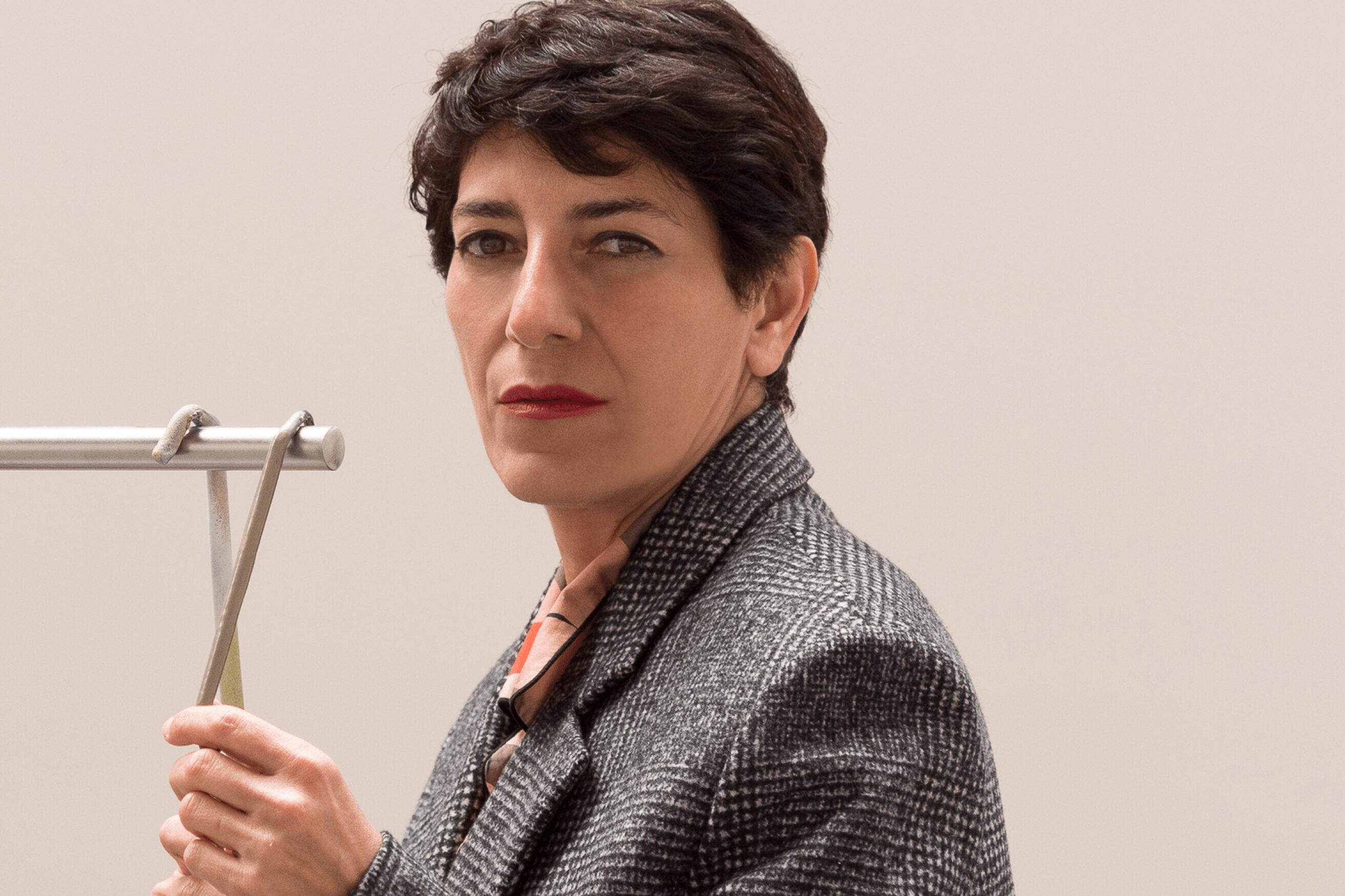 Portrait of Nairy Baghramian, she has short dark hair and a grey blazer.