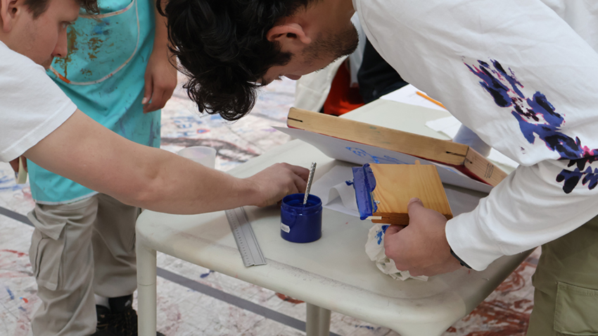 Två personer hjälps åt med att göra screentryck på textil.