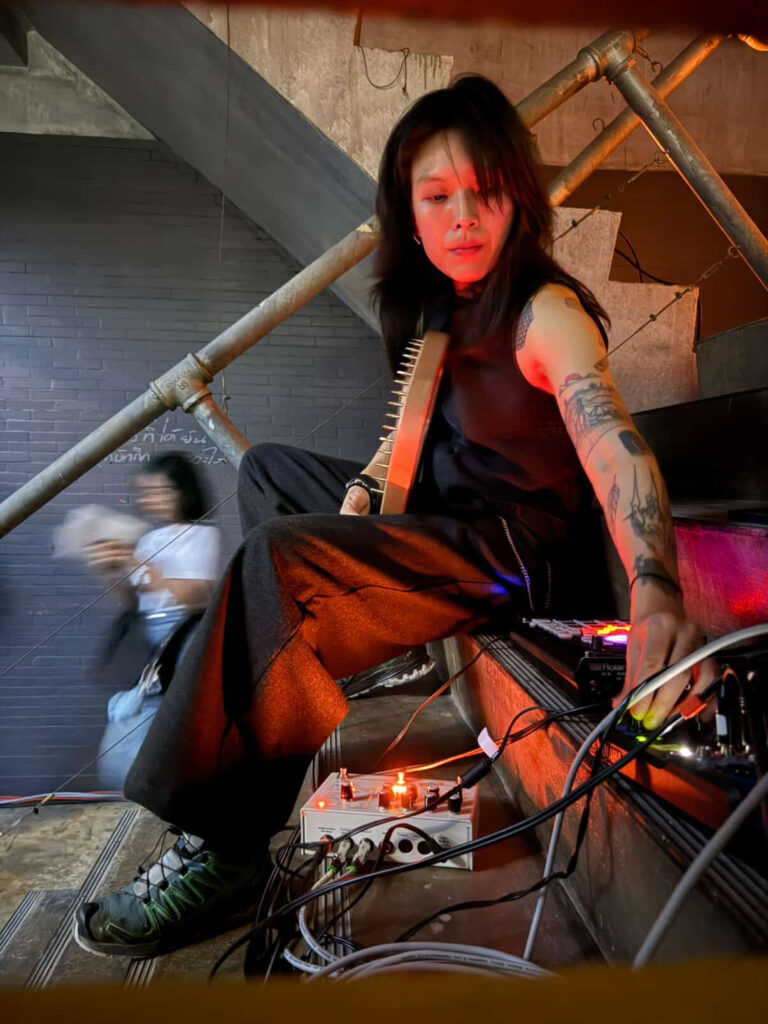 Ljudkonstnären Liew Niyomkarn sitter och skapar musik och mixar i en trappa.