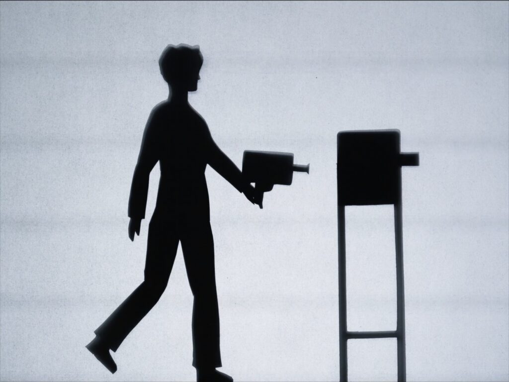 Skuggbild av en person som går med en gammaldags filmkamera i handen.