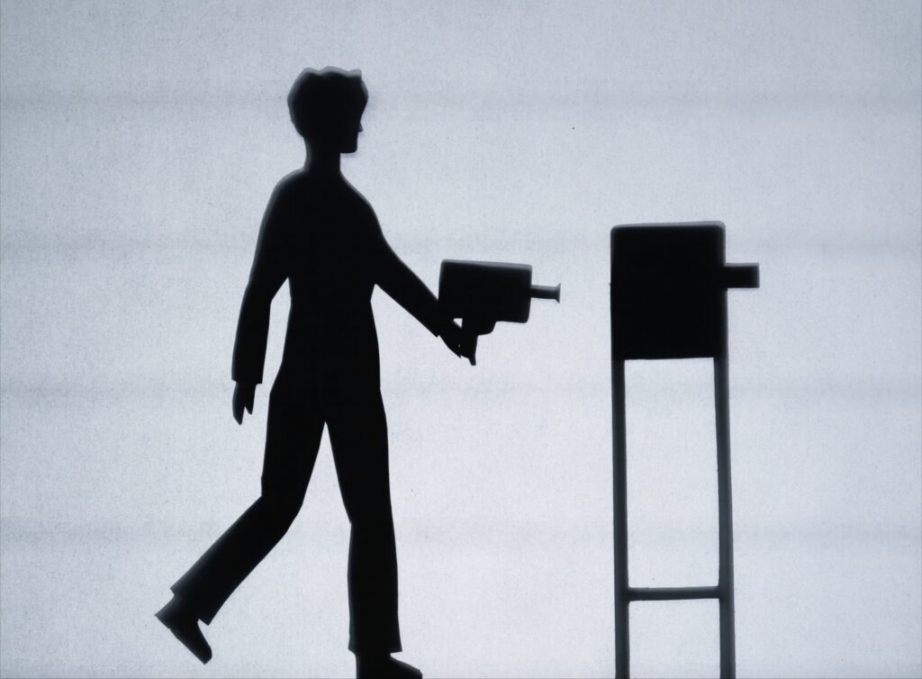 Skuggbild av en person som går med en gammaldags filmkamera i handen.