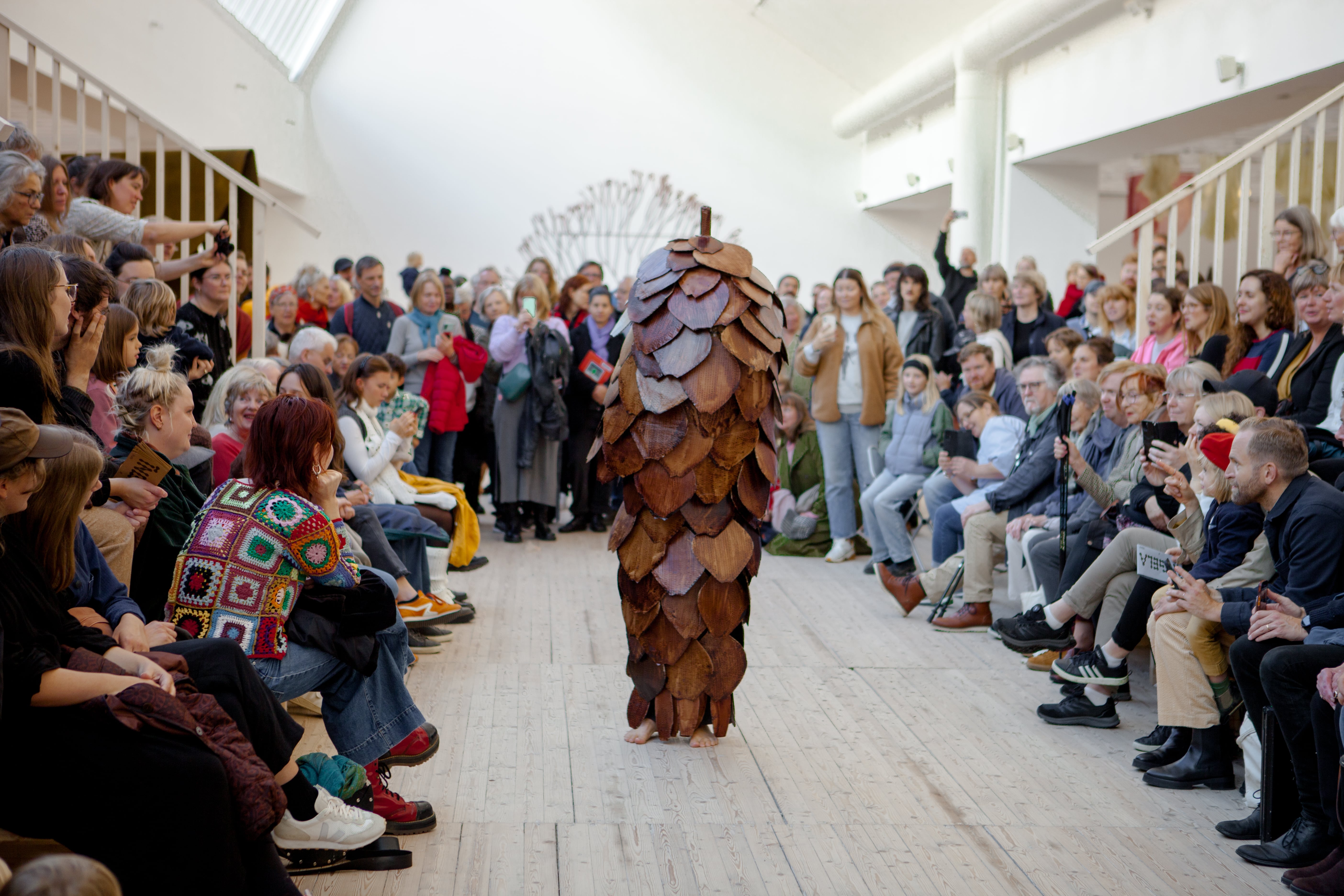 En stor grupp besökare beskådar Ingela ihrmans performance "Granen vandrar" i Konsthallen.