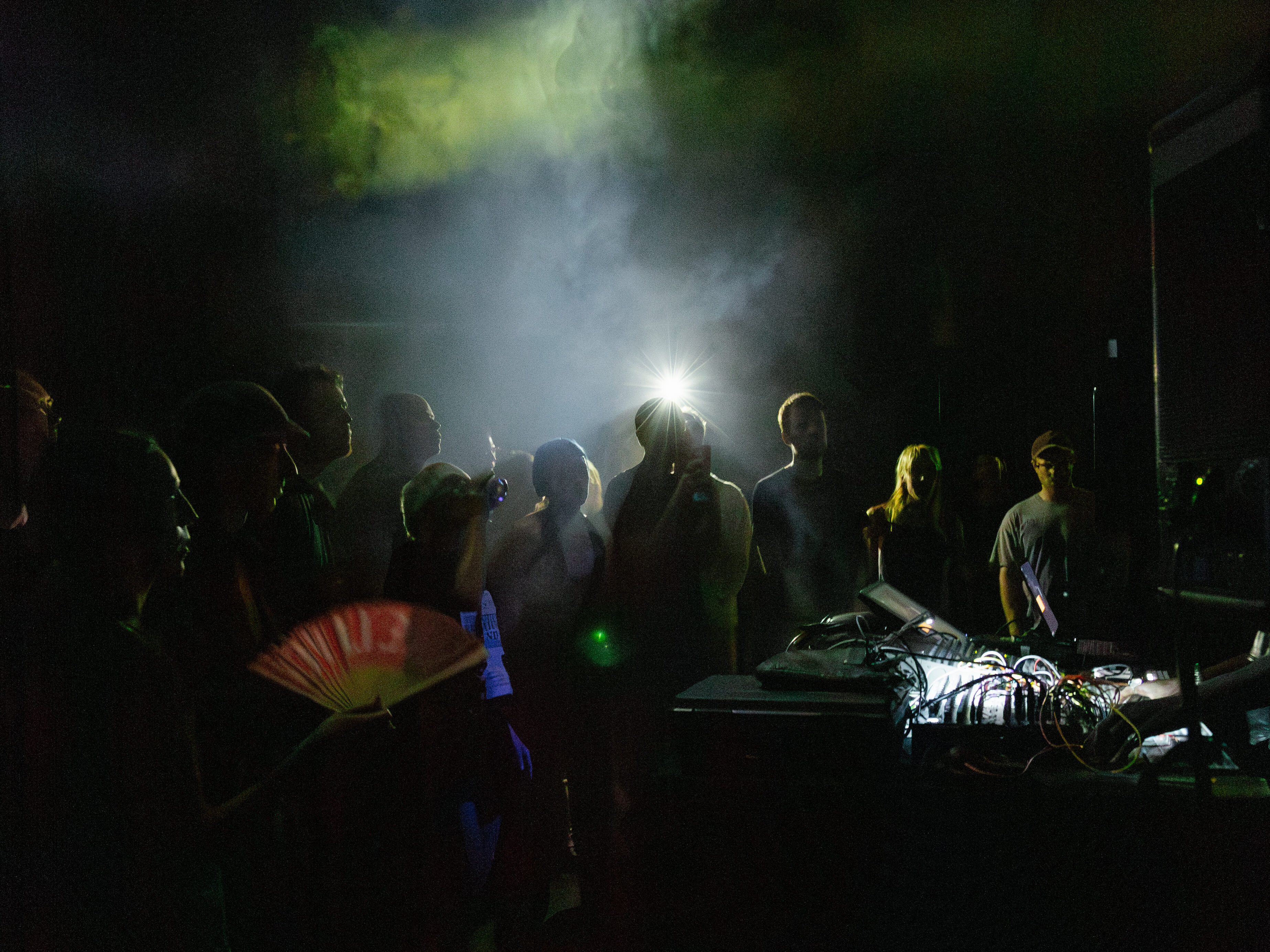 Ett mörkt, rökfyllt rum. En folkmassa står framför ett DJ-bås.