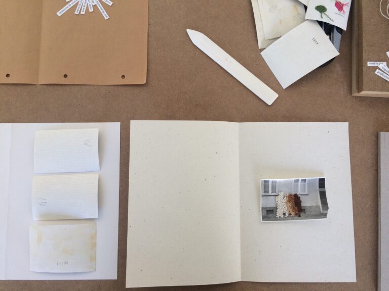 Ett arbetsbord med papper, fotografier och annat material som kan ingå i en Artist´s Book.